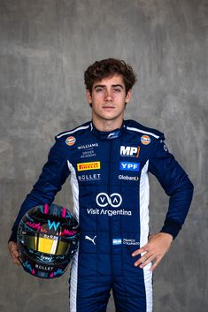 a man in a racing suit holding a helmet