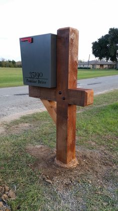 a wooden post with a mailbox attached to it on the side of a road