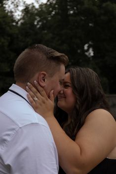 a man and woman embracing each other in front of trees