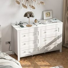 a bedroom with a white dresser and gold sunburst decoration on the wall above it