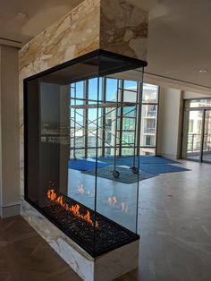 a fire place in the middle of a room with glass walls and doors on both sides