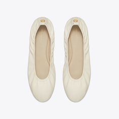 Originally released in 2011, the Eddie ballet returns with subtle updates. Characterized by an elasticized topline that softly hugs the foot, an ultra-comfortable cushioned footbed and a rubber sole that adds traction and flexibility, the reimagined Eddie is distinguished by clean lines and minimalism. A slightly narrower toe refines the slipper-like silhouette and split T's featured on the back pull tabs reflect the pared-down branding featured across our ready-to-wear collection. Crafted in partnership with a Leather Working Group-certified tannery, supporting high standards in leather manufacturing and chemical management. Elegant Cream Ballet Flats With Round Toe, Luxury Leather Ballet Flats In Cream, Luxury Cream Leather Ballet Flats, White Leather Slip-on Ballet Flats, Tory Burch Ballet Loafers, Designer Flats, Semi Annual Sale, Handbag Shoes, Footwear Design Women