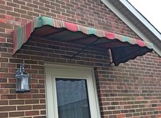 an awning on the side of a brick building next to a door and window