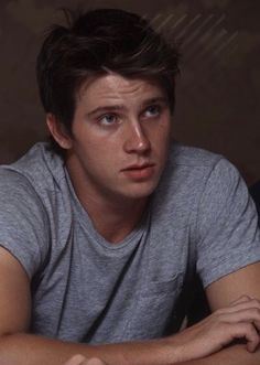 a young man sitting at a table with a coffee cup