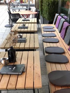 the tables are lined up outside with laptops and coffee mugs on them,