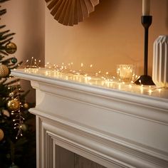 a decorated christmas tree next to a fireplace with candles and ornaments on the mantel