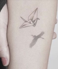 a woman's arm with an origami bird tattoo on it