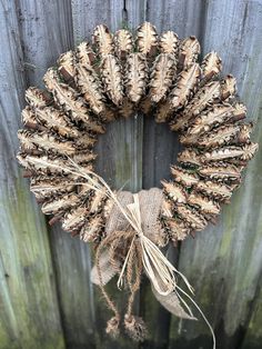 a close up of a wreath on a wooden fence with burlocks and twine