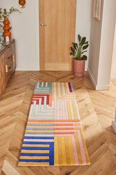 a multicolored rug on the floor in front of a door with potted plants