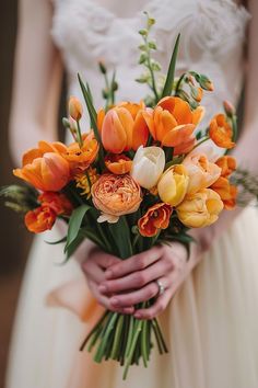 a bride holding a bouquet of orange and white flowers