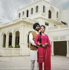 a man and woman standing in front of a white building