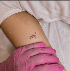 a woman with pink gloves on her leg has a tattoo that reads m and n