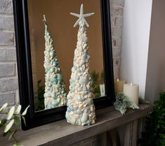 there are two christmas trees in front of the mirror and one is made out of seashells