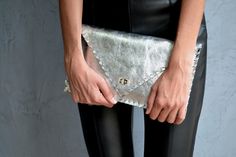 "Silver Symmetria Clutch. The perfect bag for all occasions! Ideal for cocktail and parties or for business meetings depending the size you choose. You can use it as a chic briefcase for your work or as a modern large clutch for a night out. This adorable clutch is handmade out of a genuine, lux Italian silver cow leather. -Small size fits all your essentials, wallet, keys, mobile, cosmetics etc. -Large size fits a 15\" laptop, ipad, portofolio etc and it's perfect as a file folder or as modern Silver Leather Clutch Evening Bag, Elegant Silver Leather Clutch, Leather Pouch Evening Bag For Party, Leather Pouch Clutch For Parties, Elegant Leather Envelope Evening Bag, Elegant Metallic Clutch For Everyday Use, Modern Silver Clutch For Party, Metallic Clutch For Formal Occasions, Chic Metallic Rectangular Clutch