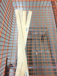 two pieces of wood sitting inside of a metal wire basket on top of a floor