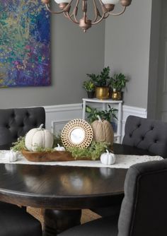 the dining room table is decorated with white pumpkins and greenery