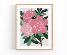 a pink flower cross stitch pattern in a wooden frame on a white wall, with green leaves