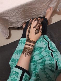 a woman with henna on her arm laying down next to a white table cloth