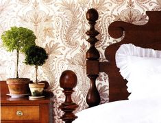 a bed with a wooden headboard and two potted plants on top of it