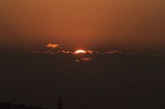 the sun is setting behind some clouds in the sky