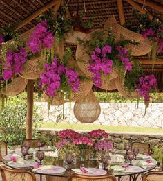 an outdoor dining area with wicker furniture and flowers hanging from the ceiling