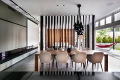 a dining room table and chairs in front of a large window with vertical striped blinds