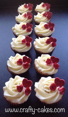 several cupcakes with white frosting and red flowers on them are arranged in a row