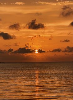 the sun is setting over the ocean with some clouds in the sky and one boat out on the water