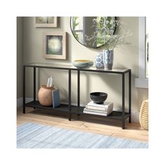 a console table with books and vases on it in front of a round mirror