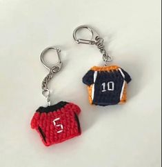 two crocheted keychains with numbers on them, one is red and the other is blue