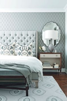 a white bed sitting on top of a wooden floor next to a nightstand and lamp