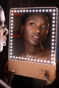 a woman is looking at her self in the mirror with light up lights on it