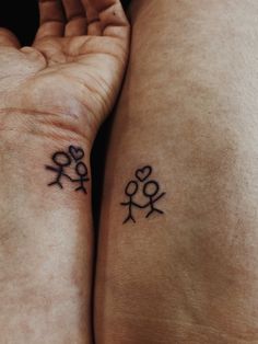 two people with matching tattoos on their arms, one holding the other's hand