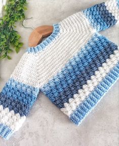 a blue and white sweater sitting on top of a table next to a wooden hanger