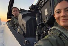 two people are sitting in the cockpit of a plane and one person is smiling at the camera