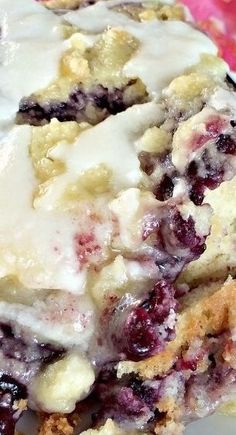 a close up of a piece of cake on a plate with icing and blueberries