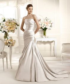 a woman in a white wedding dress standing next to a table with flowers on it