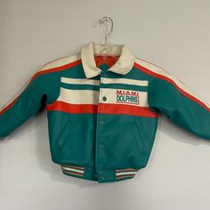 Vintage Rare Mighty Mac Sports Nfl Miami Dolphins Faux Jacket Youth 4t Teal Green Body With White Dolphin Logo Size 4t 22" Elastic Waist 12" Sleeve Zipper And Snap Closure Material: Shell 100% Pvc Simulated Leather Backing 65% Polyester/35% Cotton Lining 100% Nylon Filler 100% Polyester Care: Close Zipper, Machine Wash Cold - Inside Out, Tumble Dry Low Never Worn, No Tag White Outerwear For Game Day In Winter, White Winter Outerwear For Game Day, Winter Team-colored Track Jacket For Sports, Team-colored Long Sleeve Track Jacket For Game Day, 90s Green Sports Windbreaker, Dolphin Logo, 90s Blue Sports Track Jacket, 90s Multicolor Sports Outerwear, White Dolphin