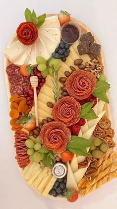 a platter filled with lots of different types of cheeses and fruit on top of each other