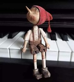 a wooden toy sitting on top of a piano keyboard with a red scarf around it's head