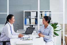 two women sitting at a desk talking to each other