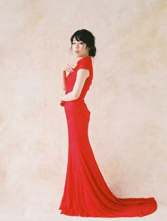 a woman in a long red dress poses for a photo with her hand on her hip