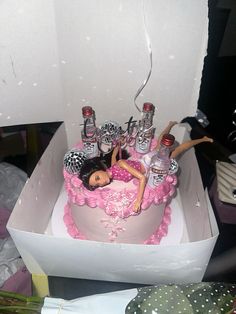 a barbie doll is laying on top of a pink birthday cake with bottles in it