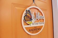 a welcome to our home sign hangs on the front door with a butterfly hanging from it's side