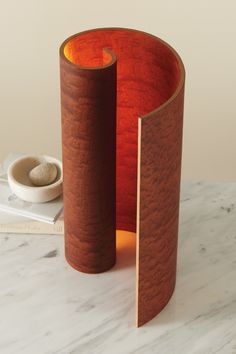 two wooden vases sitting on top of a white table next to a book and bowl