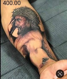 a man's arm with a jesus tattoo on it and his hand holding something