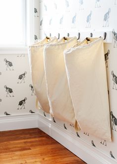 three bags hanging on the wall in front of a window with horses drawn on it