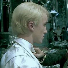 a man with blonde hair is looking at another man's face in a mirror