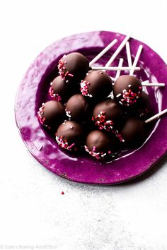 chocolate covered candies with sprinkles on a purple plate, ready to be eaten