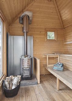 the inside of a wooden cabin with a stove and two benches in front of it